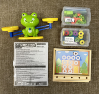 A frog scale with tiny frogs, worksheets, and plastic numbers are pictured.