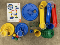 The Marble Run Jr has large yellow, blue, and green plastic pieces including ramps, funnels, circles, and marbles.