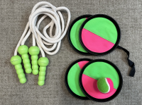 4 pink and green Velcro paddles are pictured with a pink and green tennis ball and two jump ropes with green handles.